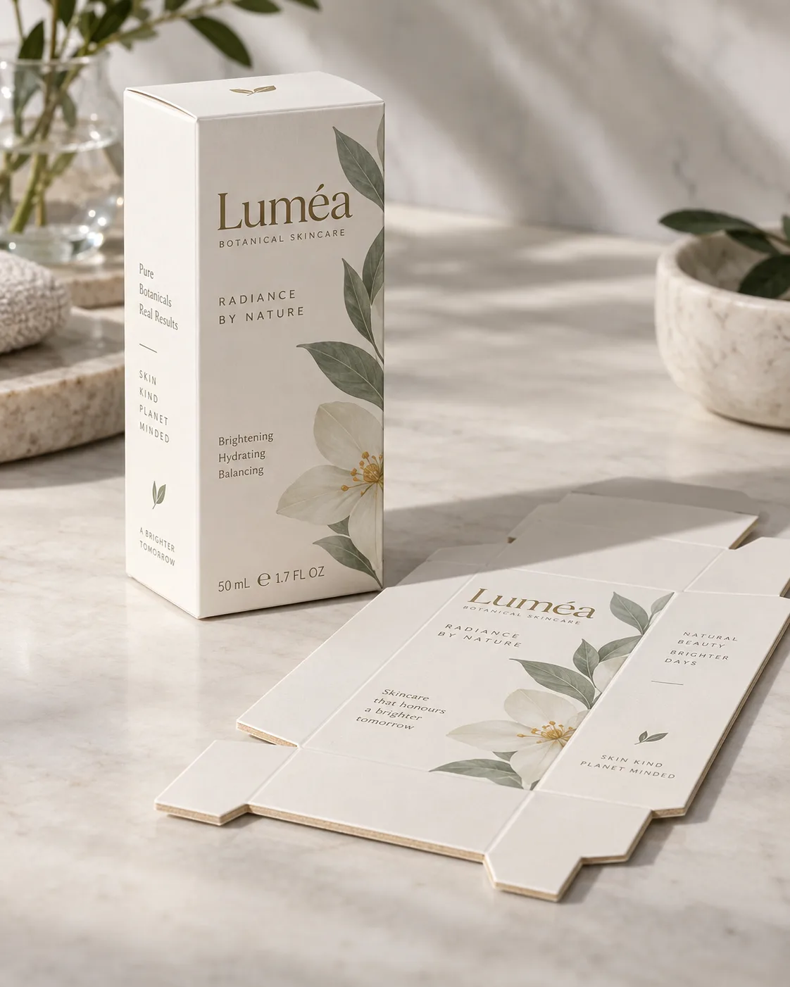A printed folding box board carton standing on a pale bench beside its flat blank, the cut edge of the blank turned to camera so the cream middle ply reads against the coated face