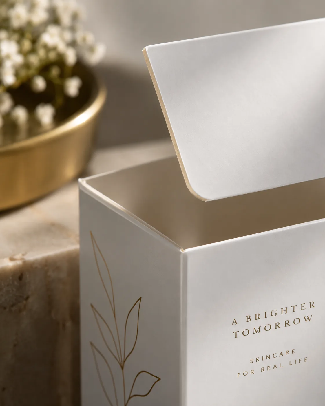 A white folding box board carton with its tuck flap standing up, the cut edge of the flap reading warm cream against the coated white face