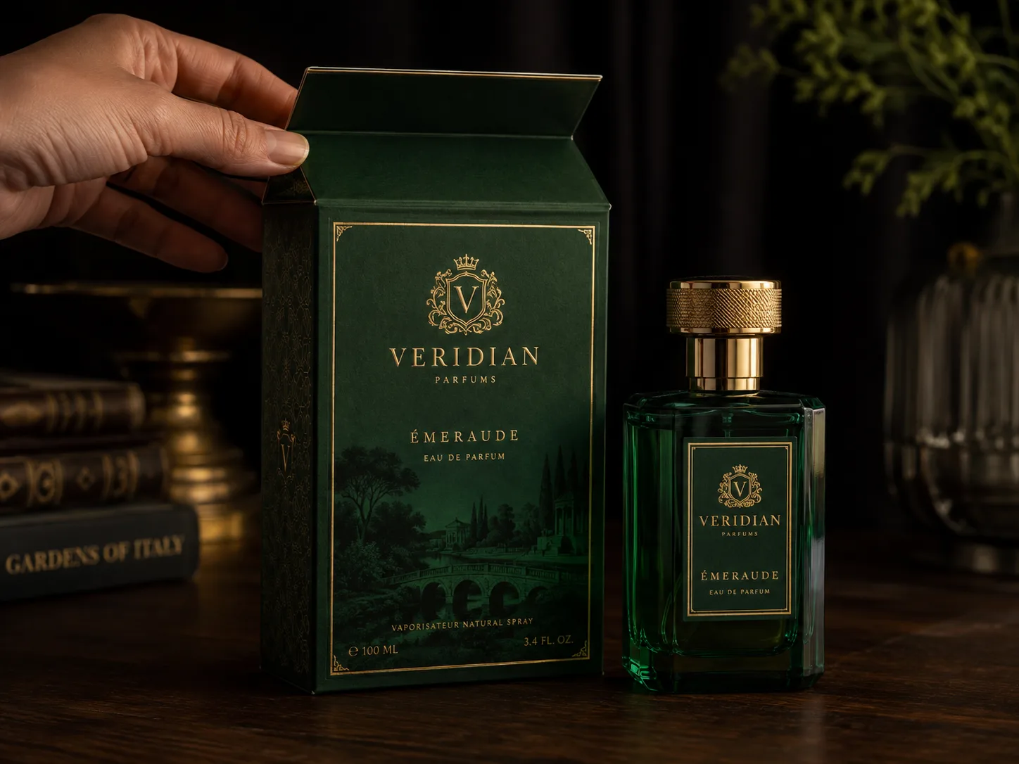 A dark green perfume carton in gold foil, ornate borders and a fine engraved scene across the front panel, standing open beside the faceted green bottle it holds.