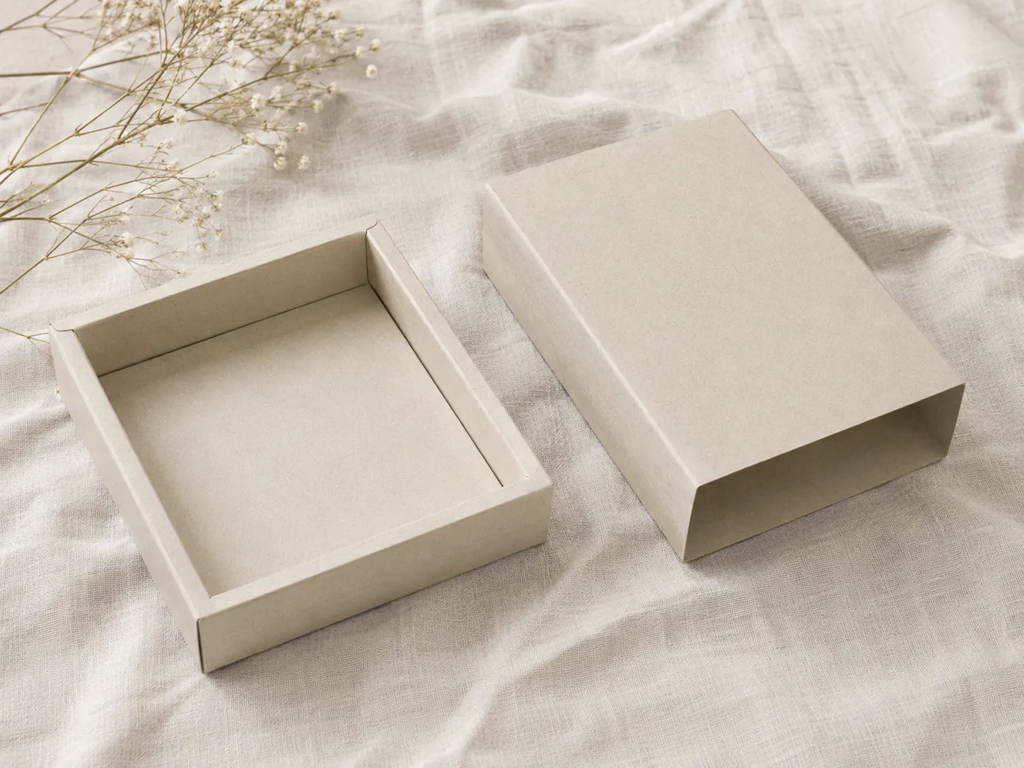 The two pieces of a kraft tray and sleeve pack laid side by side on linen, the empty tray open to camera and the outer sleeve beside it.