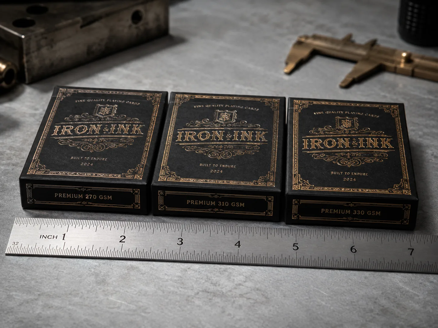 Three black tuck boxes of one design made in three board weights, standing in a row behind a steel rule